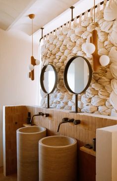 a bathroom with two sinks and mirrors in front of a wall made out of rocks