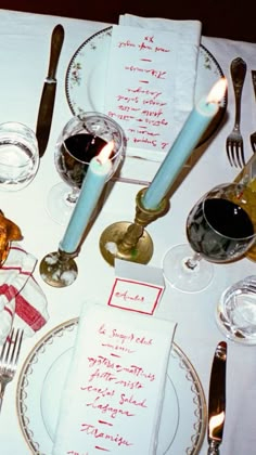 a table set with silverware, candles and menus for an elegant dinner party