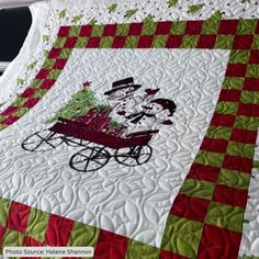 a quilted snowman riding in a red and green wagon