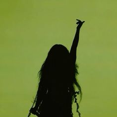 the silhouette of a woman with her arms in the air, against a green background