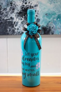 a blue bottle with a brown bow on it sitting on top of a wooden table