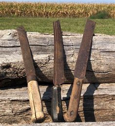 three old wooden knives sitting next to each other on top of a piece of wood