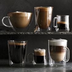 three different types of coffee cups on a shelf with one being filled with liquid and the other is empty