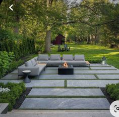 an outdoor living area with couches and fire pit in the middle, surrounded by greenery