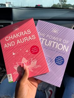 two books sitting in the passenger seat of a car, one being held up by someone's hand