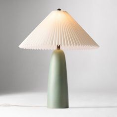 a green table lamp with a white shade on it