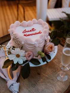 a heart shaped cake on a table with flowers and wine glasses in front of it