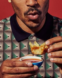 a man holding a bowl of food in his hand and making a face with his mouth