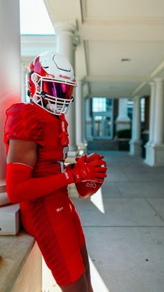 a man in a red football uniform is leaning against a wall with his hands on his hips