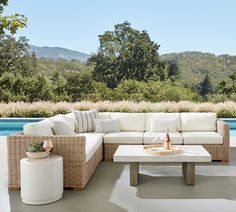 a white couch sitting next to a table on top of a patio near a pool