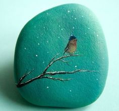 a painted rock with a small bird on it's back sitting on a tree branch