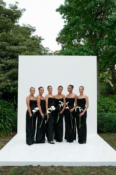 a group of women standing next to each other in front of a large white wall