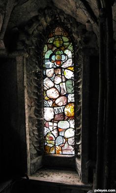 a stained glass window in the side of a stone building with exposed walls and ceiling