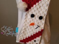 a crocheted scarf with a snowman face on it and a white t - shirt underneath