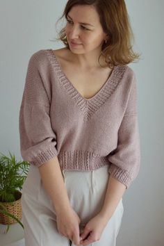 a woman wearing a pink sweater and white pants