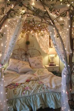 a bed covered in white sheets and lights under a canopy over it's headboard