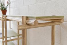 a close up of a wooden shelf near a white brick wall with a potted plant on it