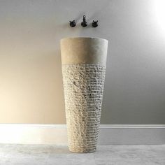 a tall white vase sitting on top of a floor next to two black knobs