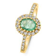 an emerald and diamond ring in yellow gold with diamonds around the band, on a white background