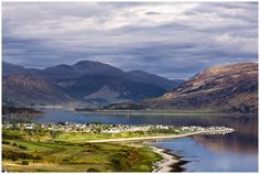 a scenic view of the mountains surrounding a lake and town in the foreground, with houses on the other side