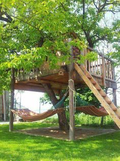 a tree house with a hammock in the yard