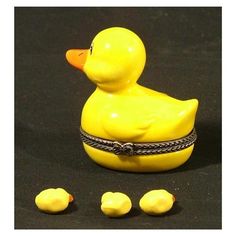 a yellow rubber duck sitting next to three little chicks on a black surface with one chick in the middle