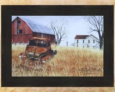 an old rusted car in a field with a red barn behind it and trees on the other side