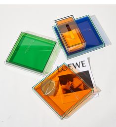 four different colored glass coasters sitting on top of a white table with an advertisement in the middle