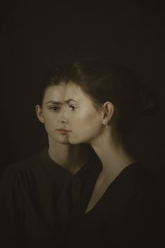 a woman with her head turned to the side, in black shirt and dark background