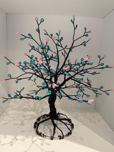 a tree with blue, pink and white balls in it's branches on display