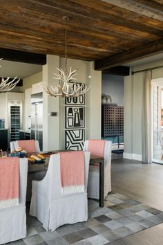 the dining room table is set with four chairs, and there are antlers hanging from the ceiling