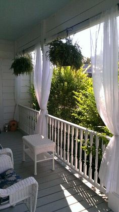 the porch is decorated with white curtains and wicker furniture