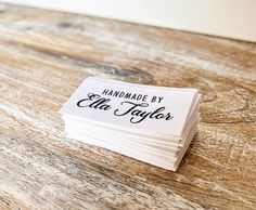 a stack of white business cards sitting on top of a wooden table covered in black ink