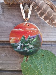 a bird is perched on top of a tree branch with a painted rock hanging from it's side