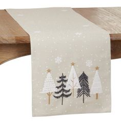 a white table runner with christmas trees and snowflakes on the top, hanging from a wooden shelf