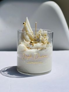 a small glass filled with white frosting and toppings on top of a table