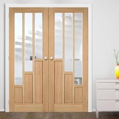 a room with two wooden doors and a vase filled with flowers on the table next to it