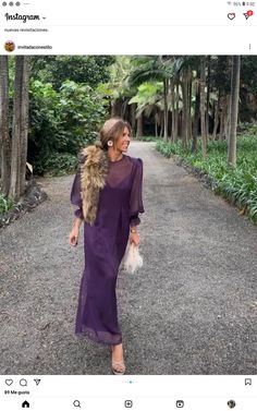 a woman in a purple dress is walking down the road with a fur stole around her neck