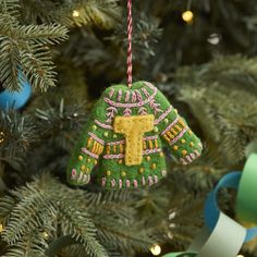 an ornament hanging from a christmas tree decorated with green and pink sweaters