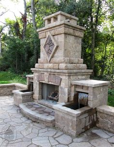 an outdoor fireplace in the middle of a stone patio