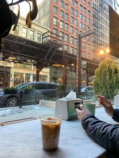 a person sitting at a table with a drink in front of them and a building