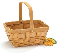 a wooden basket with handles and flowers on the floor in front of it, sitting next to a white background