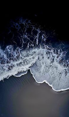 an aerial view of the ocean with waves coming in to shore and dark blue water