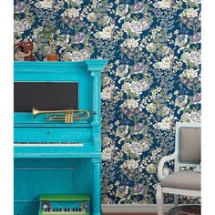 a blue piano sitting in front of a floral wallpaper