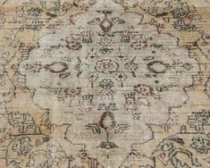 an antique rug with many different colors and patterns on it, including beiges, browns, and tans