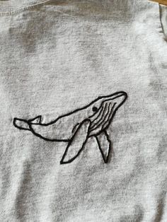 a close up of a shirt with a drawing of a whale on it's chest