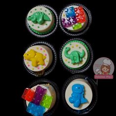 there are four cupcakes decorated with fondant and colored icing, including an elephant