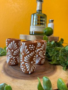 three brown and white cups sitting on top of a wooden table next to a bottle