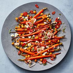 carrots, chickpeas and other vegetables on a gray plate with blue background