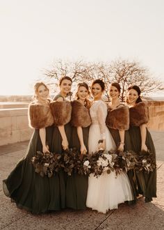 a group of women standing next to each other wearing dresses and fur stoles on their heads